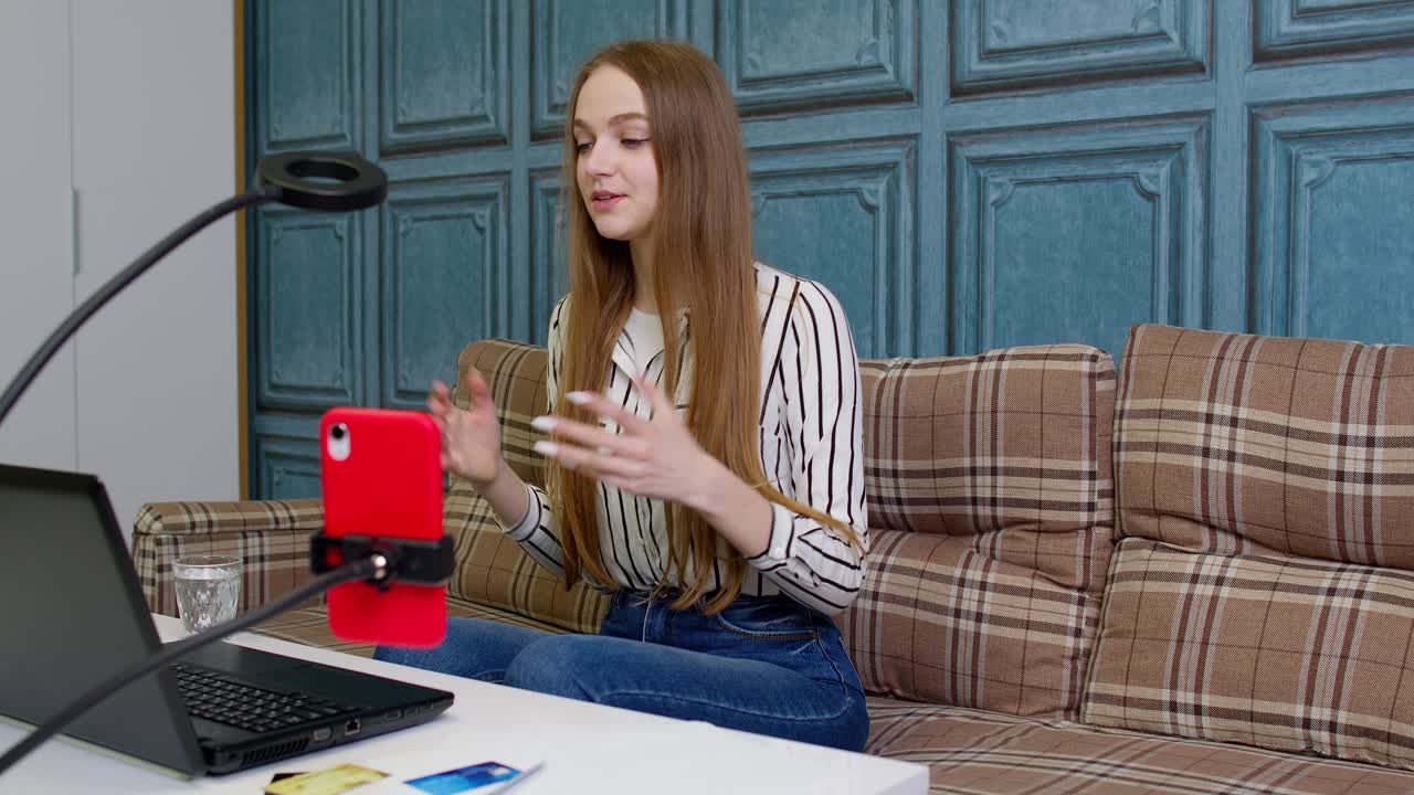 una mujer joven grabando un video en su teléfono mientras estaba sentada en un sofá
