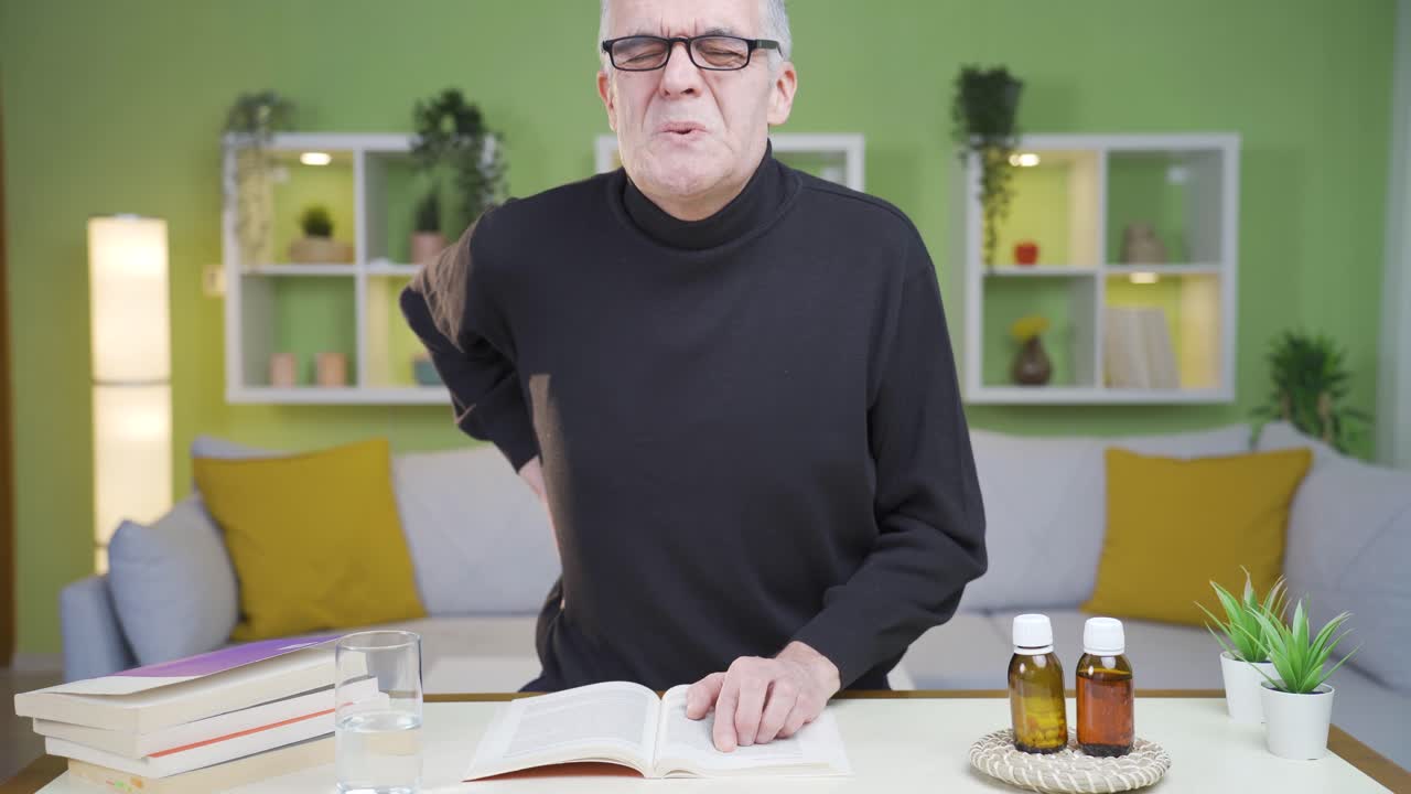 dolor de espalda baja del anciano levantándose de la mesa.