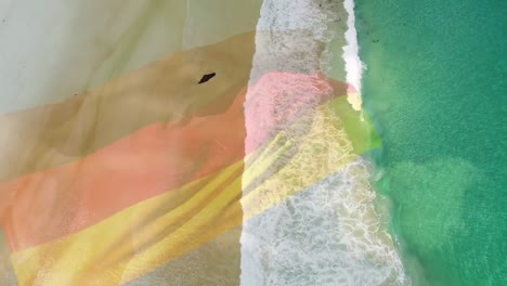 Digitale-Komposition-Einer-Wehenden-Deutschen-Flagge-Vor-Der-Luftaufnahme-Des-Strandes-Und-Der-Meereswellen