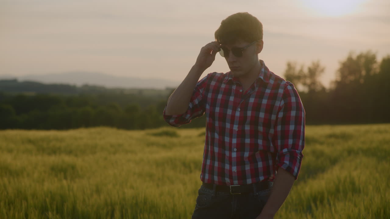 Farmer Puts on Sunglasses Against Sunset Background