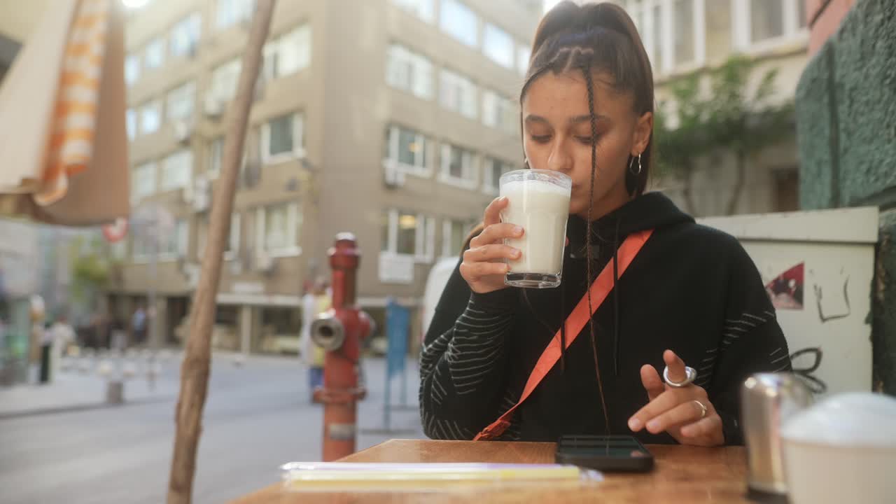 una mujer joven bebiendo una bebida en un café.