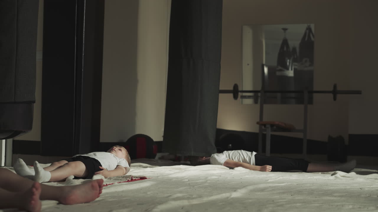 훈련 후 스포츠 센터에서 휴식을 취합니다. 피곤한 어린 아이들은 운동을 한 후 운동장에서 바닥에 조용히 누워 있습니다.