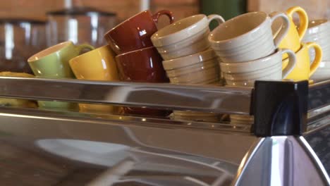 clean ceramic coffee cups stacked in pile on top of stainless coffee machine