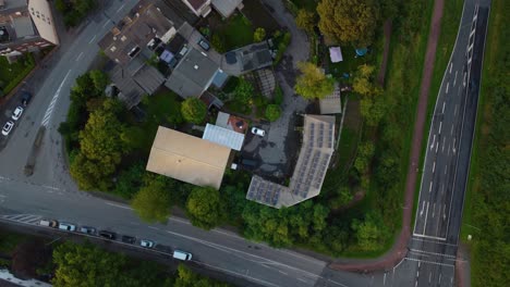 Vista-Aérea-De-Aves-Del-Techo-De-Varias-Casas-En-El-área-Rodeada-De-Frondosos-árboles-Verdes,-Caminos-Con-Autos-Estacionados-Y-Vías-De-Tren-Con-Líneas-Sobre-Vigilancia-Vecinal-Escaneando-El-área.