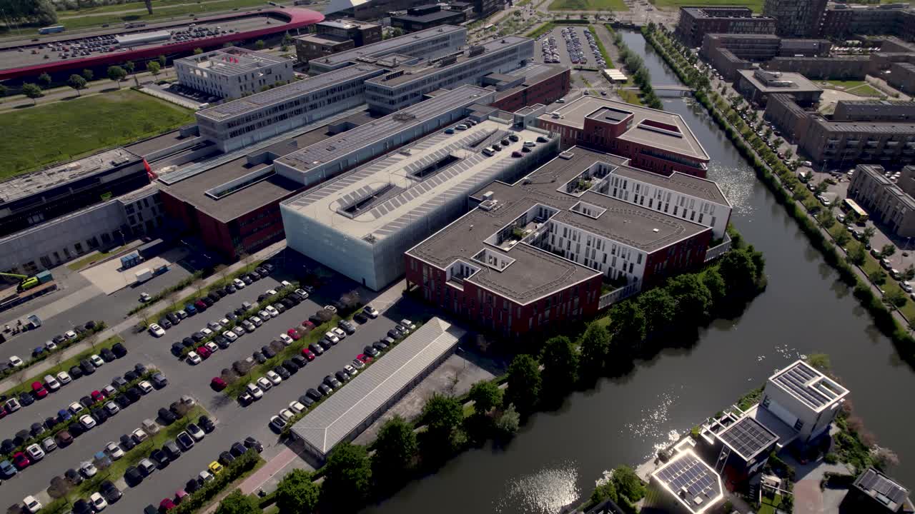 Aerial rotating pan showing Dutch Antonius hospital surrounded by water in city of Utrecht with 'The Wall' shopping in the background in contemporary Leidsche Rijn neighbourhood
