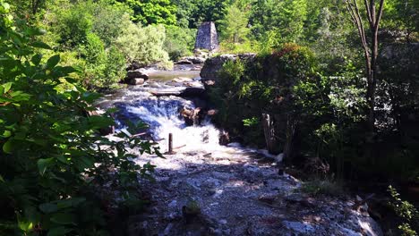 a scenic river and waterfall in a lush forest with historic ruins