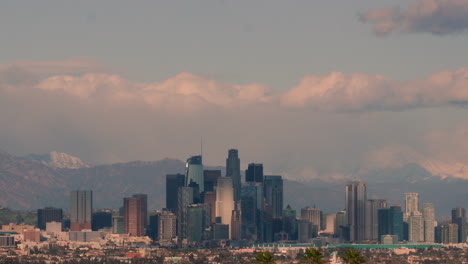 downtown la skyline from kenneth hahn state park at sunset with snowcapped mountains in the background