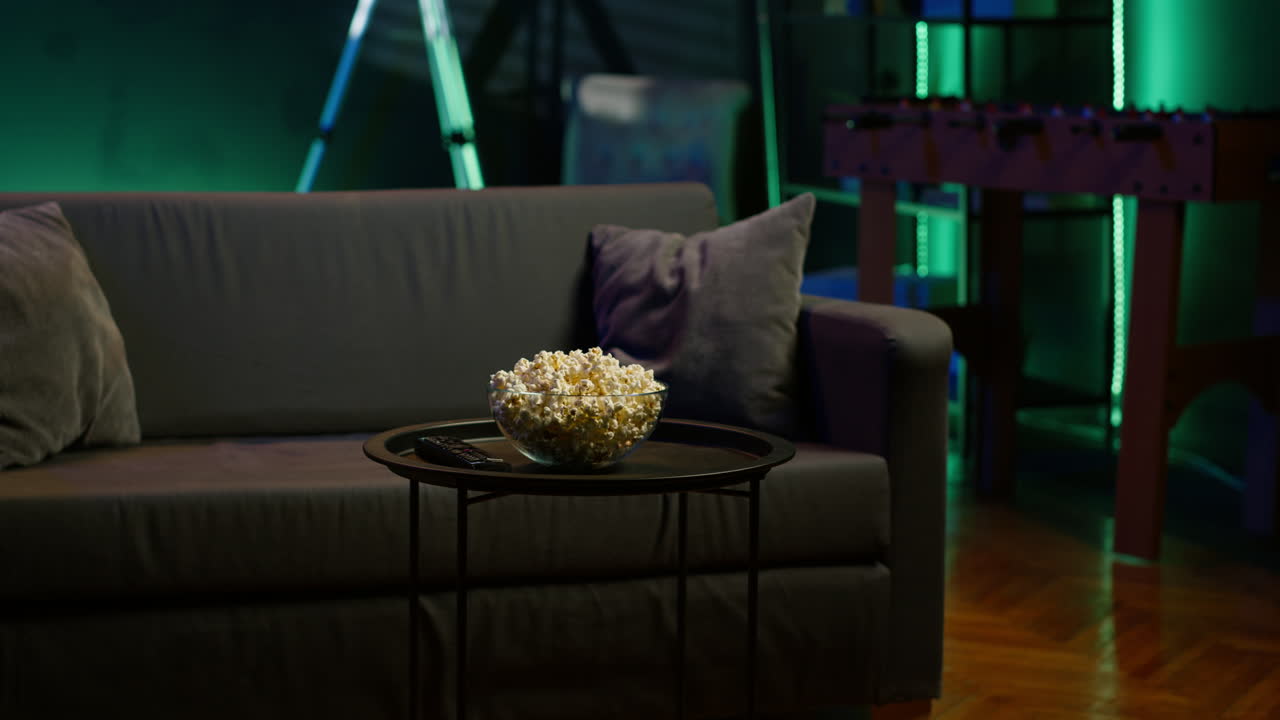 un cuenco de palomitas de maíz en la mesa en un interior residencial acogedor iluminado con neón vacío