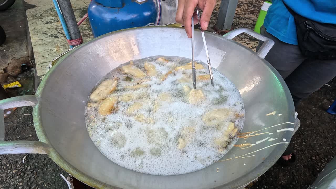 Cooking street food in a bubbling oil-filled wok