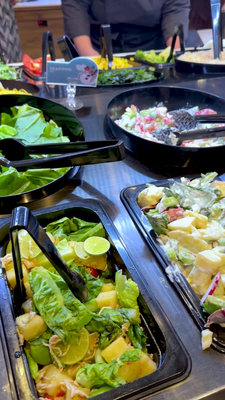 Pengunjung mengambil bahan salad berwarna-warni dari bar prasmanan swalayan yang menyala dengan gerakan kamera genggam.