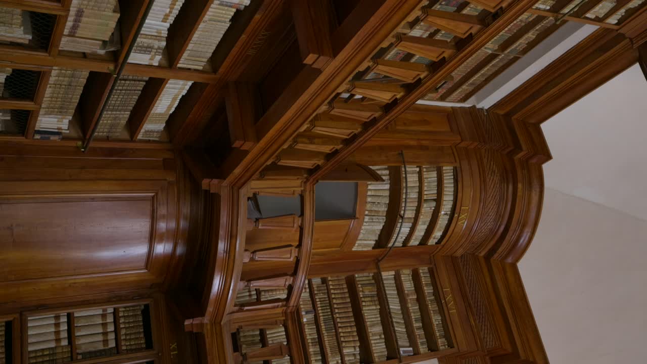 Verticale - Antiche librerie in legno con antichi volumi di libri nella Biblioteca Teresiana a Mantova, Italia