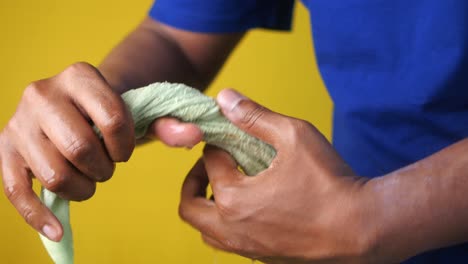 person wringing out a green towel on a yellow background