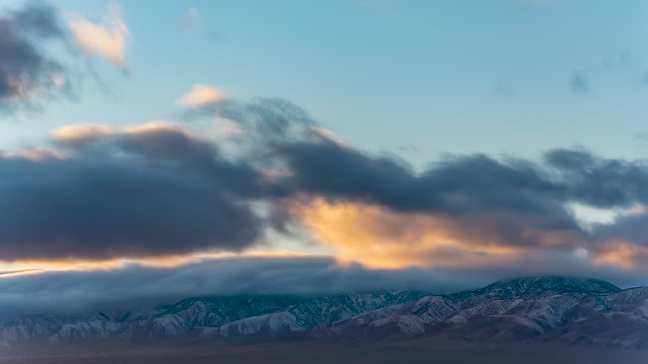 ligero polvo de nieve en las montañas del desierto de mojave con nubes al atardecer rodando sobre los picos escarpados - lapso de tiempo