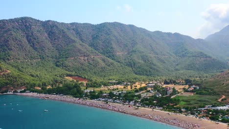 vista aérea del paisaje montañoso seco de la playa de adrasan en turquía en un caluroso día de verano mientras la gente disfruta del día a lo largo de la costa mediterránea