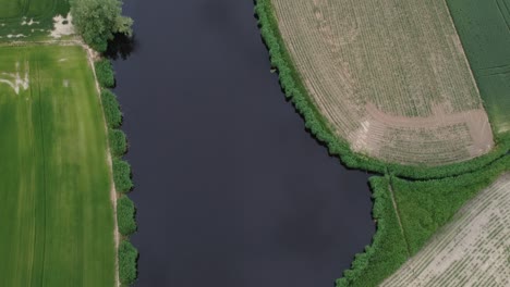 drone reveal view of river surrounded by vast arable land