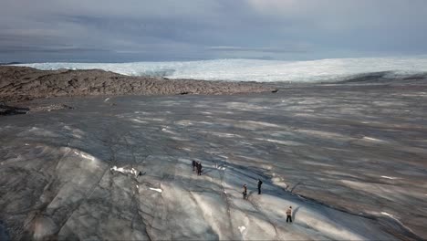 Vista-Aérea,-Volar-Sobre-Las-Personas-Que-Caminan-Hacia-La-Izquierda-En-La-Capa-De-Hielo-En-El-Punto-660,-En-Las-Afueras-De-Kangerlussuaq,-Groenlandia