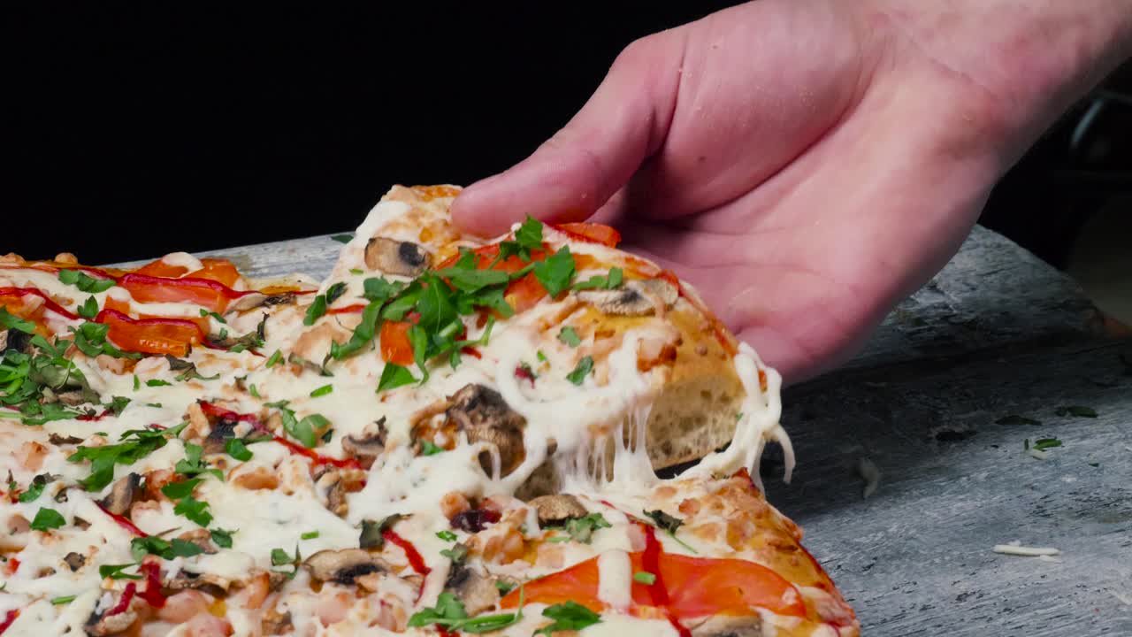 una mano sostiene una deliciosa rebanada de pizza con queso derretido