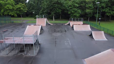 aerial view flying reverse above fenced skate park ramp in empty closed public playground