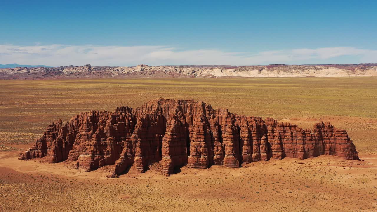 formación masiva de roca roja que se eleva en medio del desierto muerto del salvaje oeste en utah, estados unidos de américa - retroceso del carro aéreo