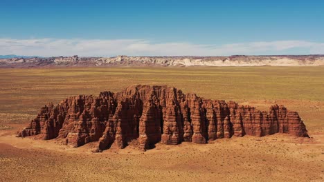 formación masiva de roca roja que se eleva en medio del desierto muerto del salvaje oeste en utah, estados unidos de américa - retroceso del carro aéreo