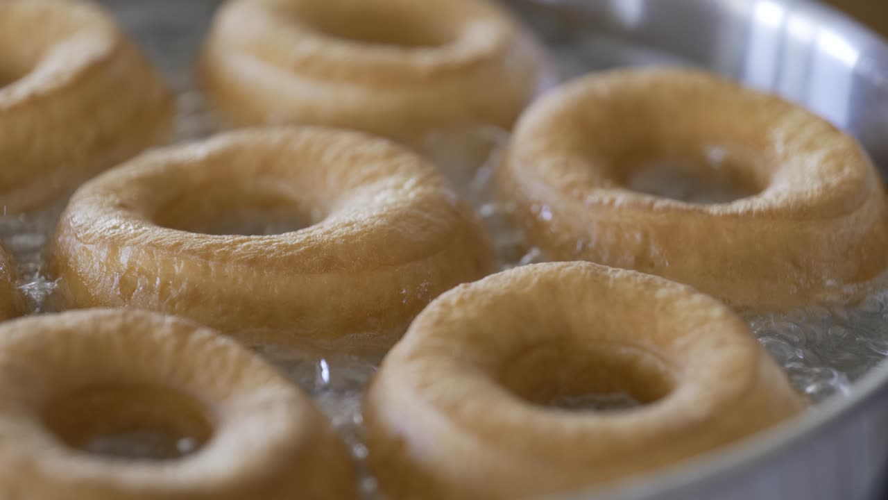 primer plano de donuts dorados frescos fritos en aceite caliente