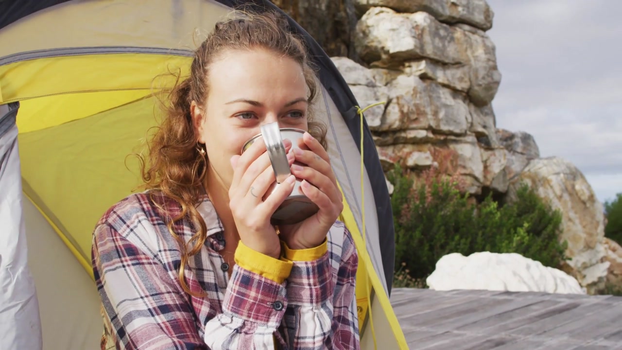 Woman camper holding mug by tent, social media bubbles appearing around her, driving engagement