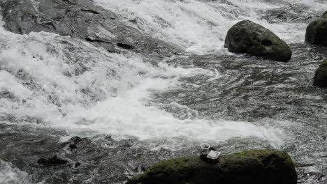 Taza-De-Café-O-Té-De-Plástico-Colocada-Junto-A-La-Fascinante-Cascada-Goa-Rang-Reng-En-Bali,-Indonesia