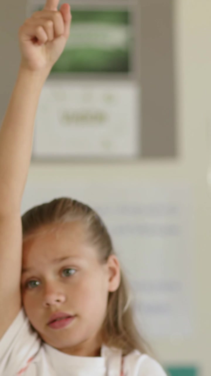 Vertical video: Raising pupil lifting right arm, pointing index finger at board, desk, green sleeve