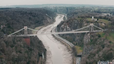 Aerial-shot-of-the-Clifton-suspension-bridge-circling-around-over-the-River-Avon,-Bristol,-during-overcast-cloudy-day