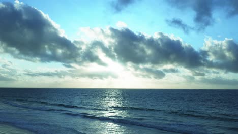 the waves of the ocean arrive peacefully on a beach under a cloudy sky