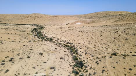 Drone-Volando-Rápido-Y-Bajo-Sobre-El-Desierto-Rocoso-Y-Un-Excursionista-Con-Equipo-Completo,-Bastones-Para-Caminar-Y-Mochila