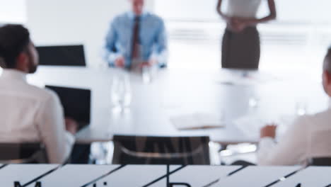 Pull-Focus-Shot-Of-Businesswoman-Giving-Boardroom-Presentation-Viewed-Through-Meeting-Room-Window-In-Slow-Motion