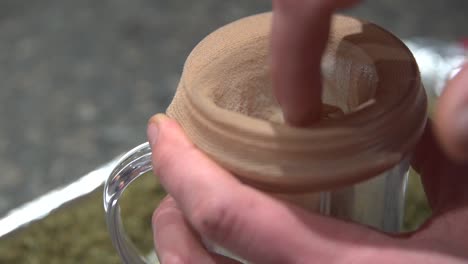 the cloth strainer put in a small glass ready for extraction of marijuana essential oil used for ailments - close up shot