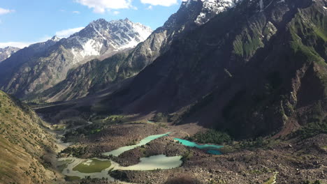 cinematic drone shot of the turquoise colored water in the mountains at naltar valley in pakistan, revealing the mountain landscape aerial shot