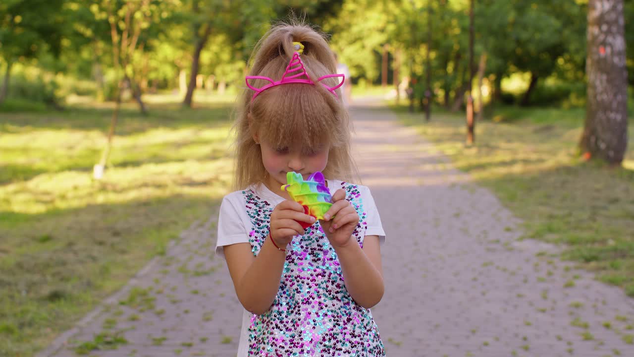 niñas apretando presiones coloridas contra el estrés pantalla táctil empujar pop es un juguete popular en el parque
