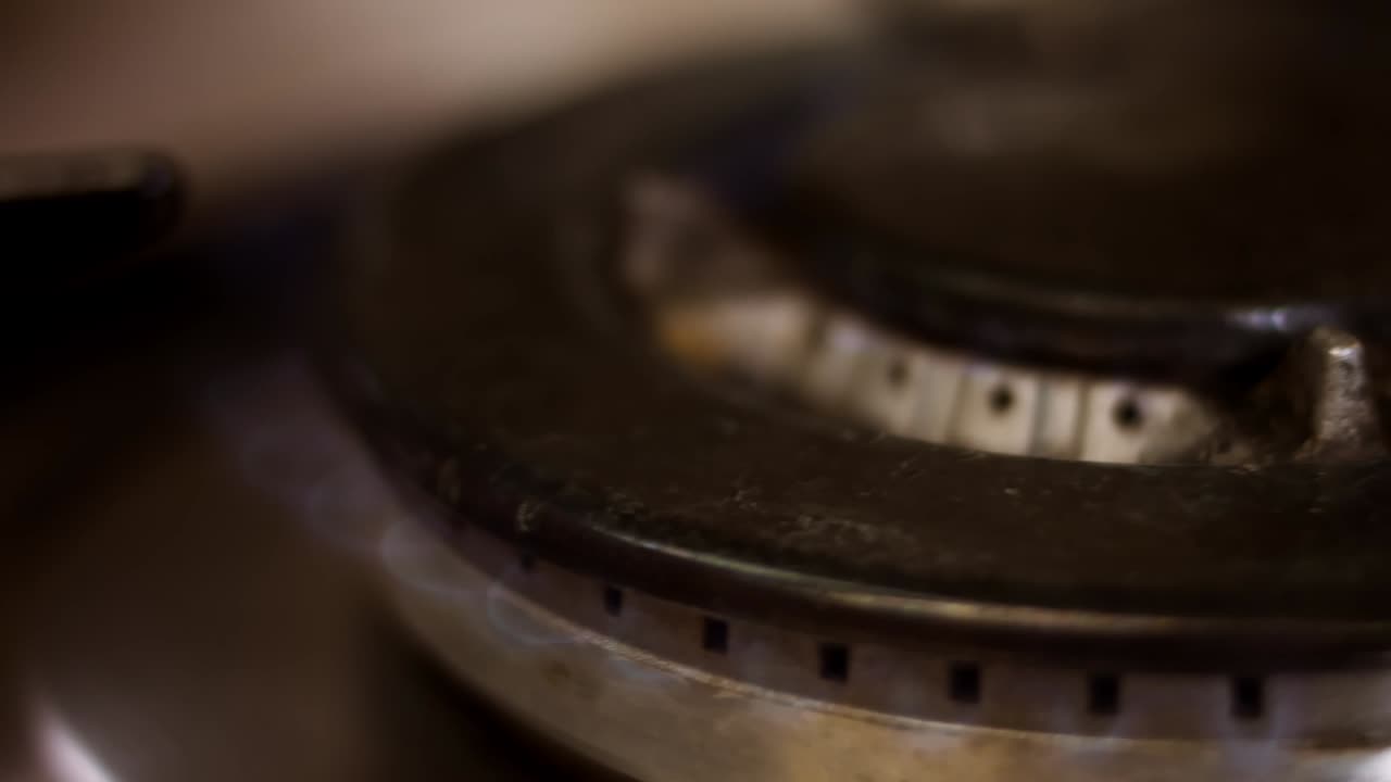 Turning on the cooktop gas cooker on black background. Kitchen burner turning on. Close up on the flame. Natural gas inflammation in stove burner, close up view. Gas burning from a kitchen gas stove