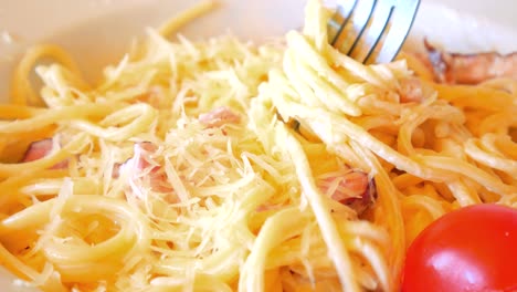 eating close up of italian pasta carbonara with parmesan and bacon.