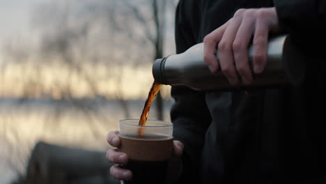 closeup of pouring coffee outside in the nature with a sunrise view