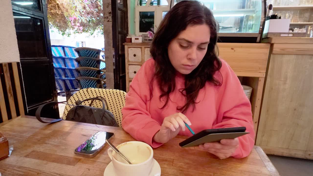Young woman drawing on tablet in cafe