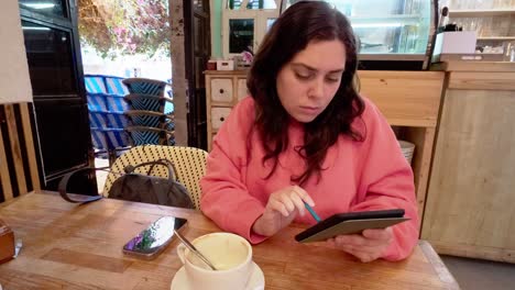 young woman drawing on tablet in cafe