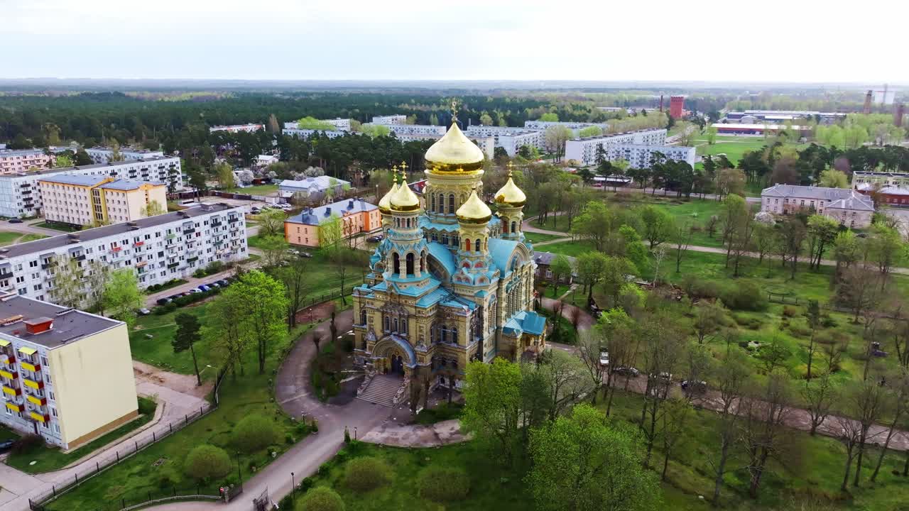 Bright blue and gold Orthodox church stands out in springtime Latvian cityscape