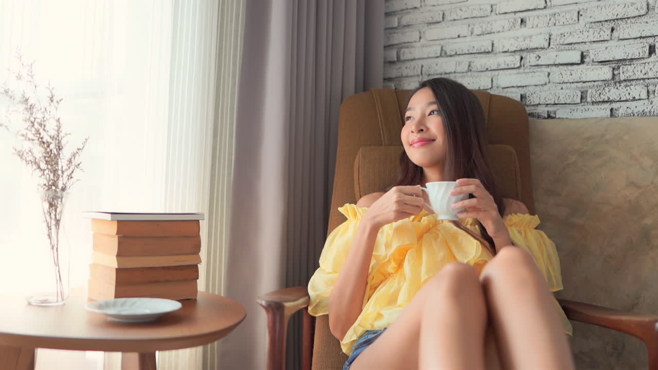 A young woman reaches for a coffee cup and drinks