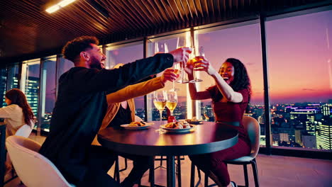 friends celebrating dinner on a rooftop bar with city view