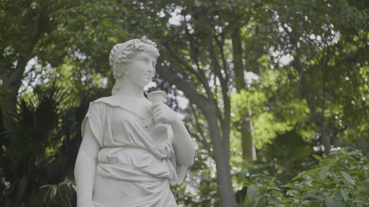 Statua di una giovane donna circondata da alberi in un parco