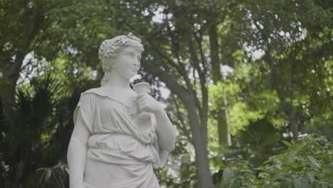 statue of a young woman surrounding by trees in a park