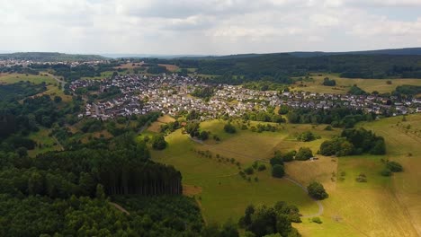 Flug-Mit-Einer-DJI-Phantom-4-Drohne-Weg-Von-Einem-Ländlichen-Deutschen-Dorf-In-Einer-Wunderschönen-Wald--Und-Feldgegend,-In-Der-Sonnenstrahlen-Den-Boden-Erhellen