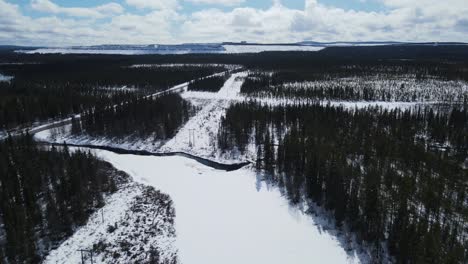 bosque de invierno con río y carretera cerca de kiruna en norrbotten, suecia