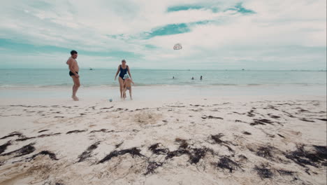 happy family of three playing a ball on the beach