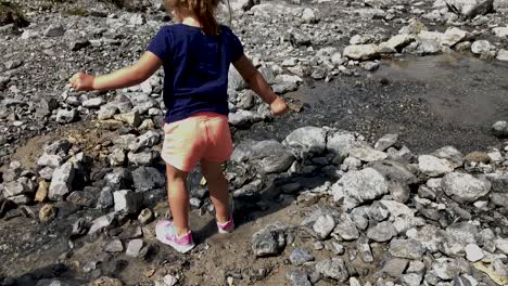 cute little girl having fun trying the water of a mountain river