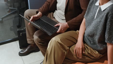 two people are seated, one holding a laptop, in a business or office setting